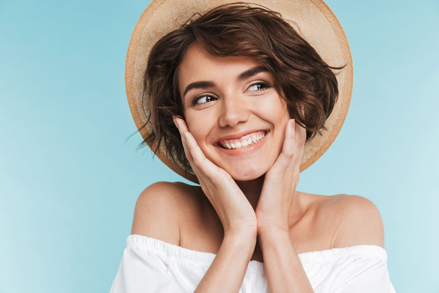 woman with hat smiling on blue background